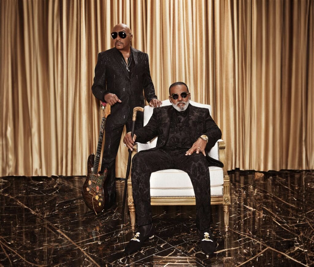 Image of the Isley Brothers posing together in front of a gold background.